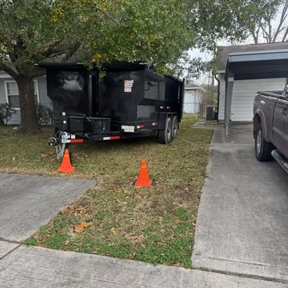Dumpster trailer parked on a residential yard beside a driveway